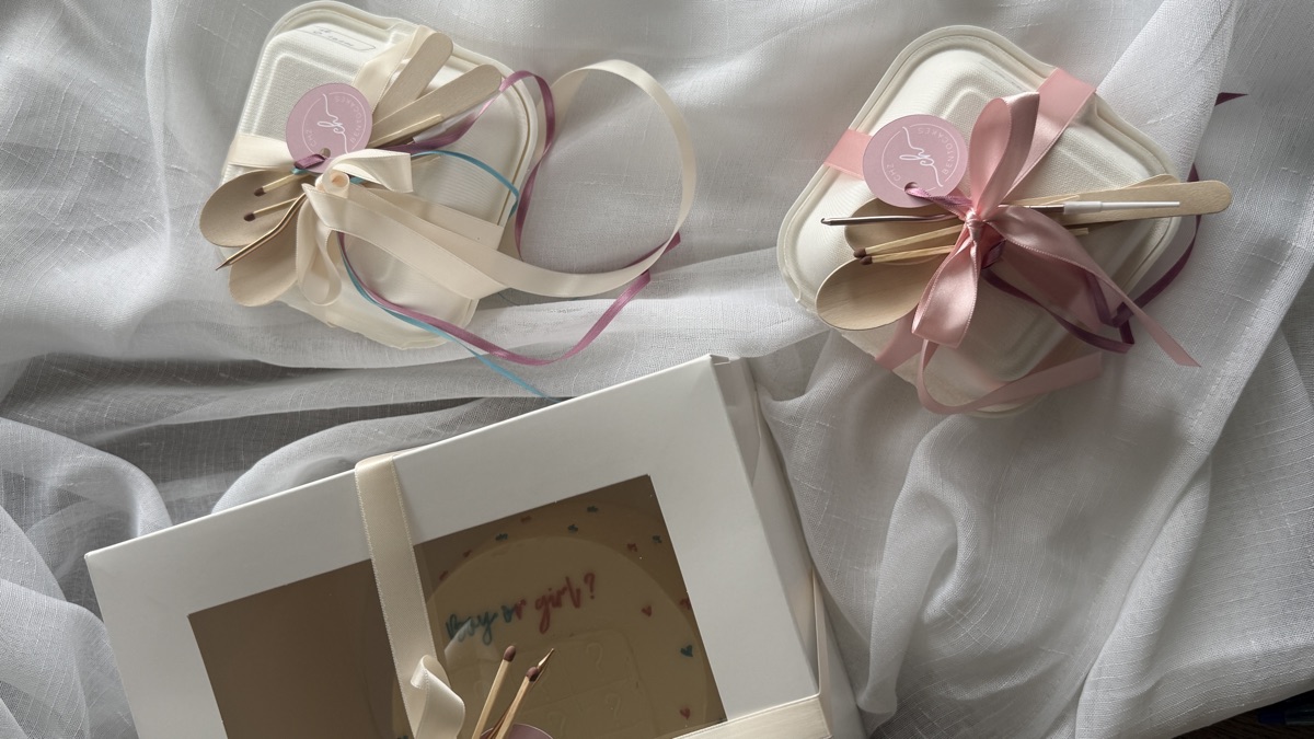 Gender reveal cakes wrapped with ribbons, candles and spoons, ready for pickup